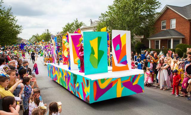 Colorful Forest Connect float moving through a Lakewood Purim parade with families along the street