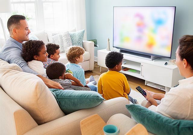 Lakewood family relaxing together in a bright living room while choosing a children's program on a television